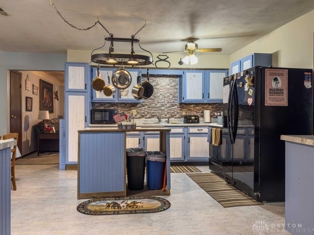 kitchen featuring backsplash, blue cabinetry, black appliances, ceiling fan, and sink