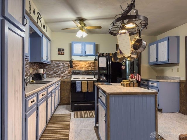 kitchen with sink, a kitchen island, decorative backsplash, white electric stove, and blue cabinets