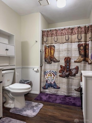 bathroom featuring vanity, hardwood / wood-style flooring, walk in shower, and toilet