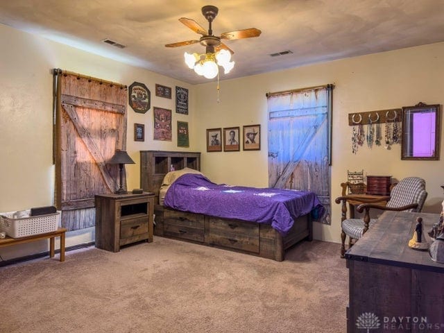 bedroom featuring a barn door, carpet flooring, and ceiling fan