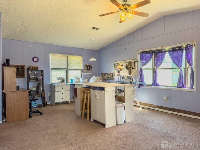 kitchen featuring pendant lighting, white cabinets, lofted ceiling, a textured ceiling, and light carpet