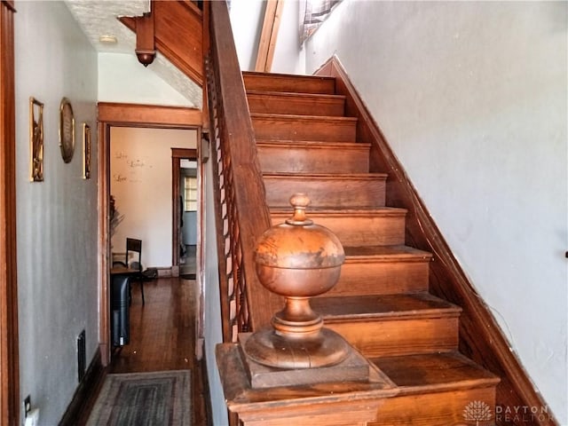 stairway with wood-type flooring and vaulted ceiling