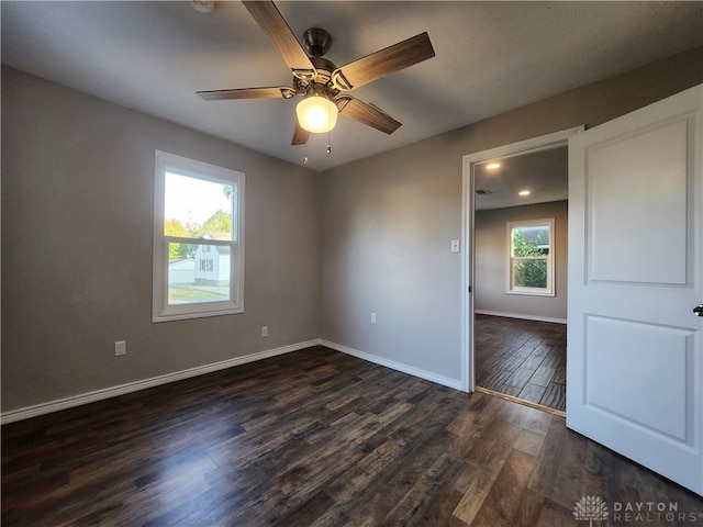 spare room featuring ceiling fan, plenty of natural light, and dark wood-type flooring