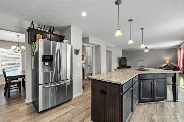 kitchen with stainless steel refrigerator with ice dispenser, light hardwood / wood-style floors, and hanging light fixtures