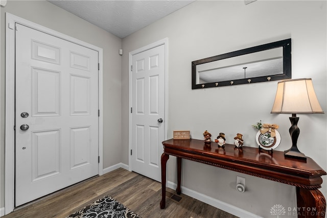 foyer entrance with a textured ceiling and dark wood-type flooring