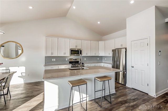 kitchen featuring an island with sink, stainless steel appliances, dark wood-type flooring, and white cabinetry