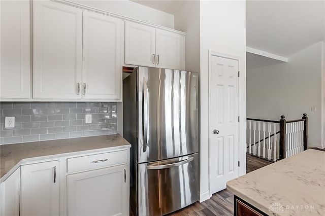 kitchen featuring tasteful backsplash, white cabinets, stainless steel refrigerator, light stone countertops, and dark hardwood / wood-style floors