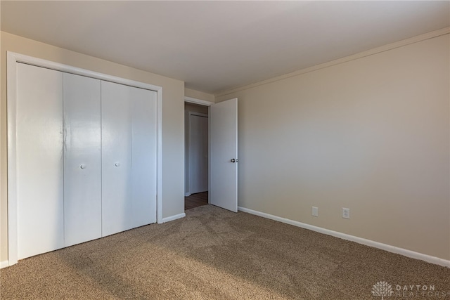 unfurnished bedroom featuring carpet floors, a closet, and crown molding