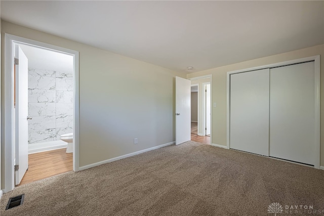 unfurnished bedroom with ensuite bathroom, a closet, and light carpet