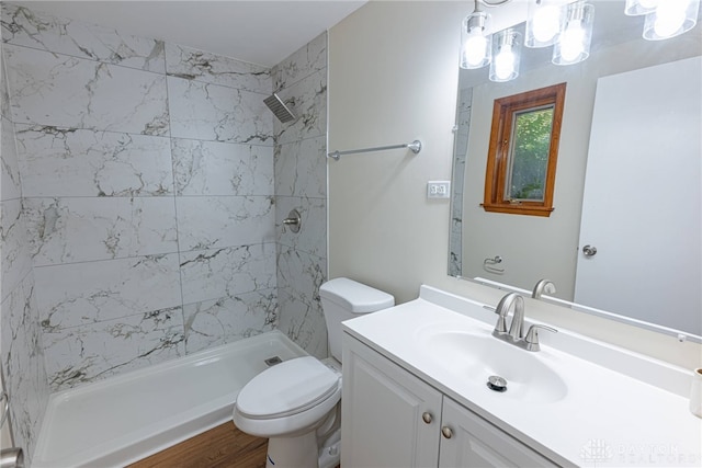 bathroom with toilet, hardwood / wood-style floors, tiled shower, and vanity