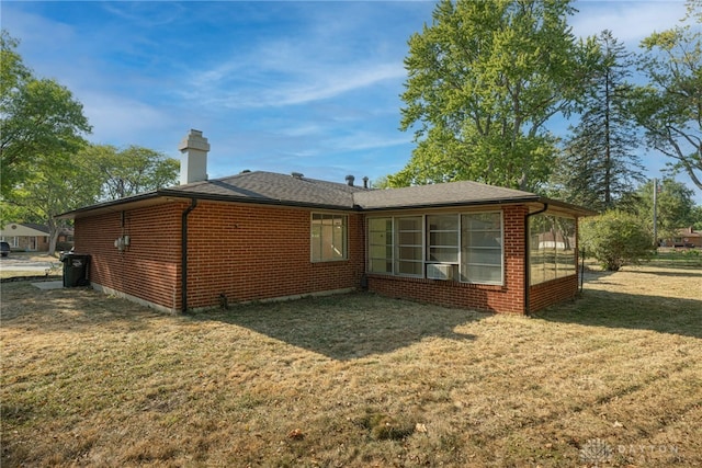 back of property with a yard and a sunroom