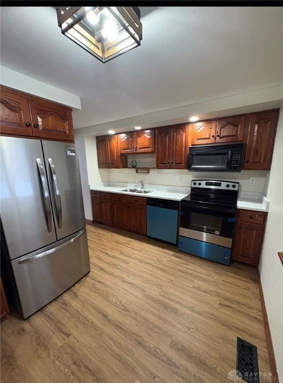 kitchen with stainless steel appliances, sink, and light wood-type flooring