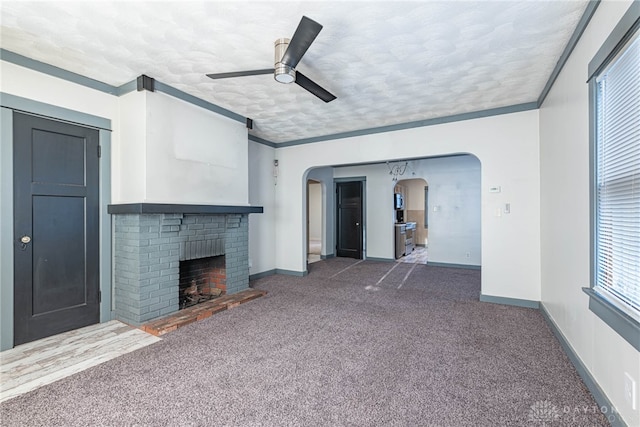 unfurnished living room with ornamental molding, a brick fireplace, ceiling fan, and plenty of natural light