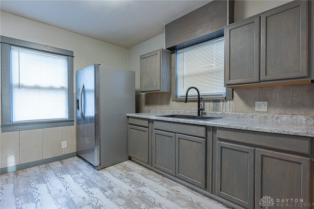 kitchen featuring light wood-type flooring, stainless steel refrigerator with ice dispenser, and sink