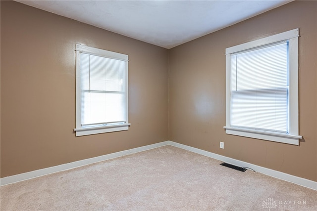 unfurnished room with a wealth of natural light and light colored carpet