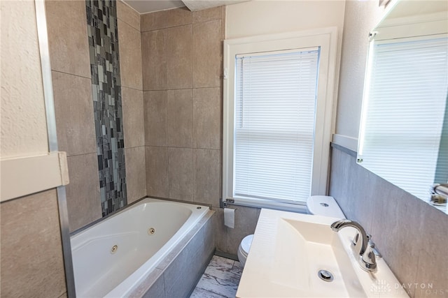 bathroom with tiled bath, sink, and toilet