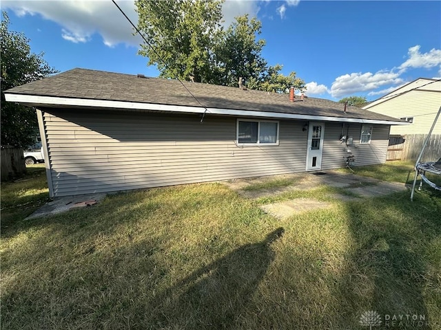 back of property with a trampoline and a lawn