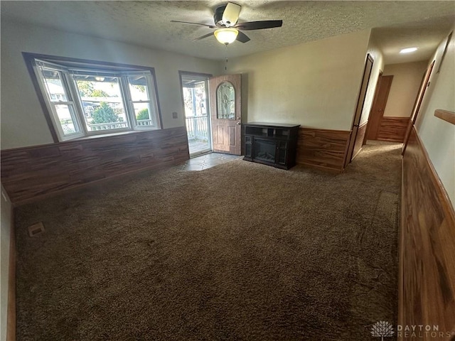 unfurnished living room with ceiling fan, carpet, and a textured ceiling