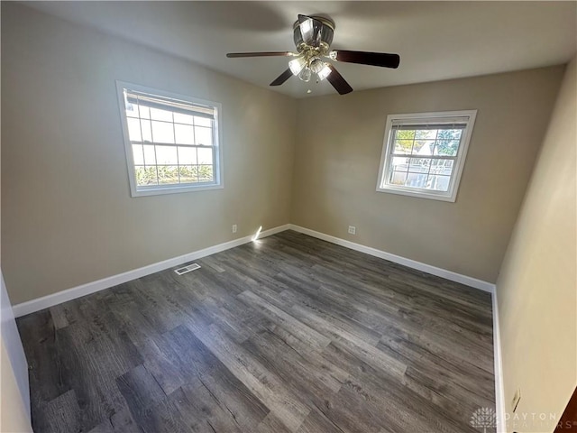 empty room featuring plenty of natural light, dark wood-type flooring, and ceiling fan