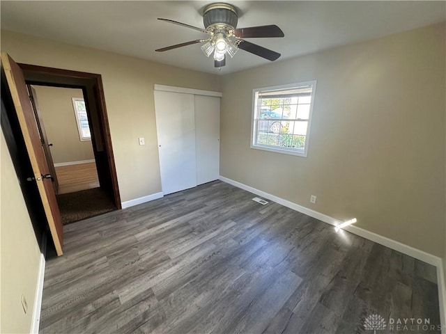 unfurnished bedroom featuring ceiling fan, dark hardwood / wood-style floors, and a closet