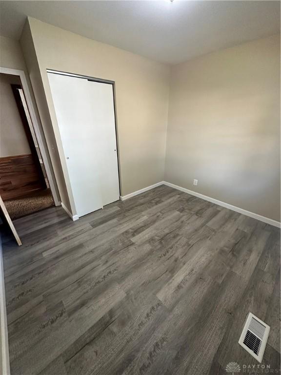 unfurnished bedroom with dark wood-type flooring and a closet