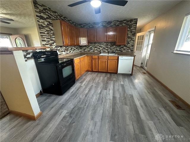 kitchen featuring black electric range oven, sink, decorative backsplash, white dishwasher, and a textured ceiling