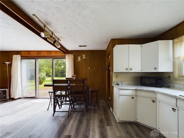 kitchen with wooden walls, white cabinets, and dark hardwood / wood-style flooring