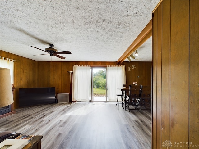 living area featuring hardwood / wood-style floors, ceiling fan, a textured ceiling, and wood walls