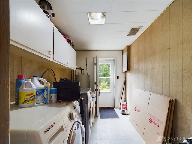 clothes washing area with cabinets, independent washer and dryer, electric water heater, and wooden walls