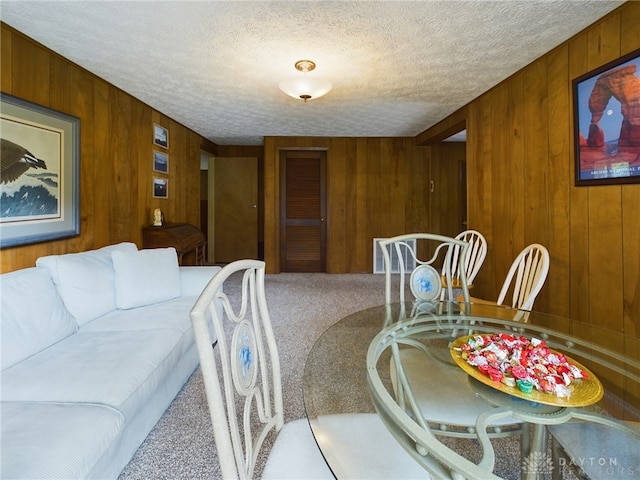 carpeted dining area featuring wood walls and a textured ceiling