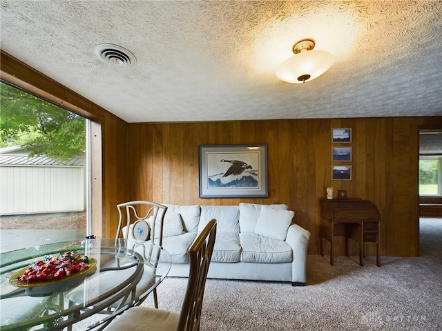 carpeted dining room featuring wooden walls and a textured ceiling