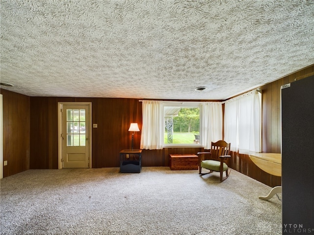 unfurnished room with carpet floors, a textured ceiling, and wooden walls