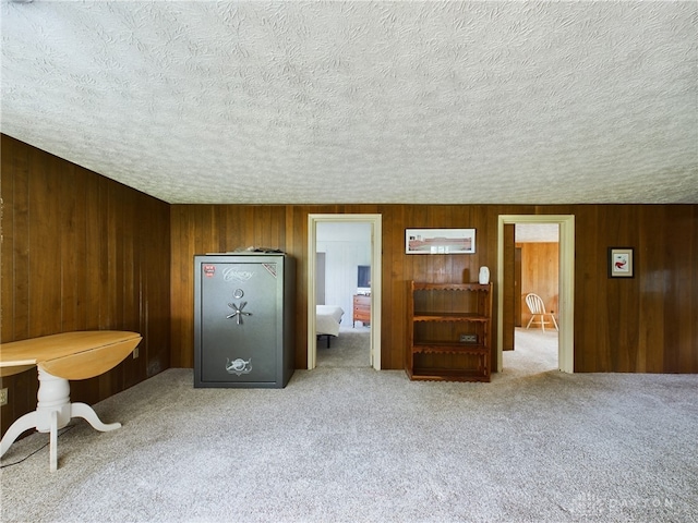 interior space featuring wooden walls, light carpet, and a textured ceiling