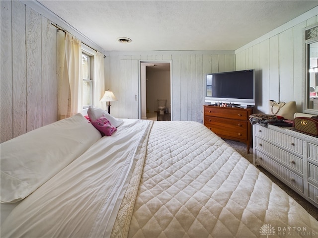 bedroom with a textured ceiling, wooden walls, and carpet