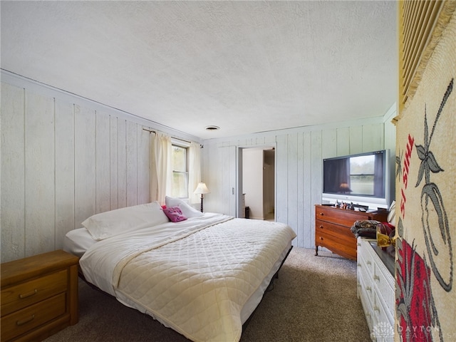 carpeted bedroom featuring wood walls and a textured ceiling