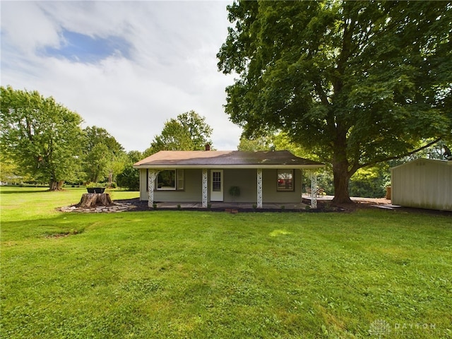 rear view of house with covered porch, a storage unit, and a lawn