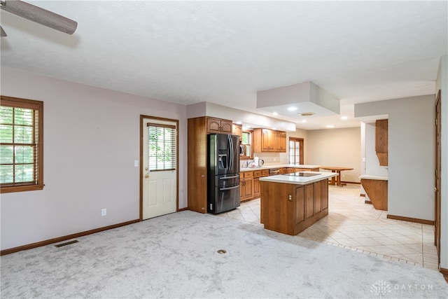 kitchen with stainless steel refrigerator with ice dispenser, a kitchen island, light colored carpet, and a wealth of natural light