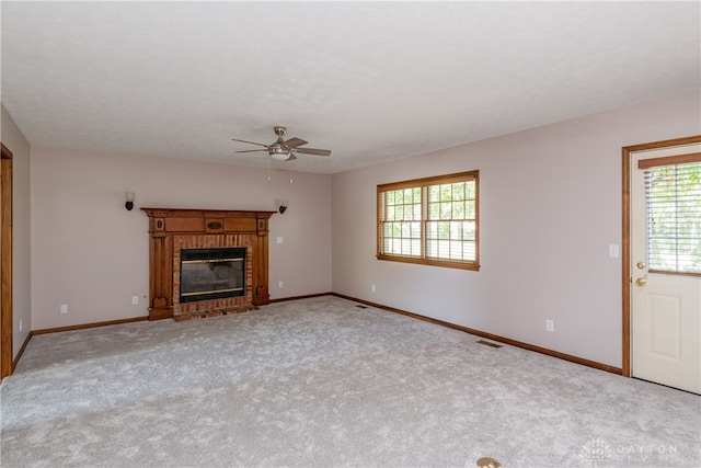 unfurnished living room with a textured ceiling, a fireplace, ceiling fan, and light colored carpet