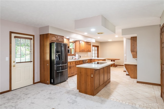 kitchen with sink, kitchen peninsula, a kitchen island, appliances with stainless steel finishes, and light colored carpet