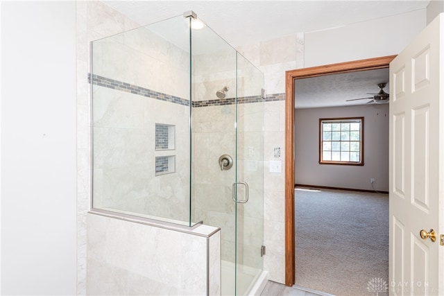 bathroom featuring ceiling fan and a shower with shower door