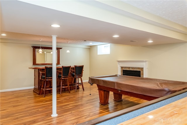 recreation room with bar area, hardwood / wood-style floors, a tiled fireplace, and pool table