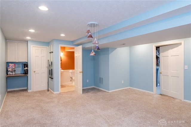 basement featuring light carpet and a textured ceiling