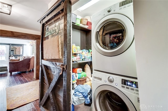 laundry area featuring stacked washer and clothes dryer and dark hardwood / wood-style floors