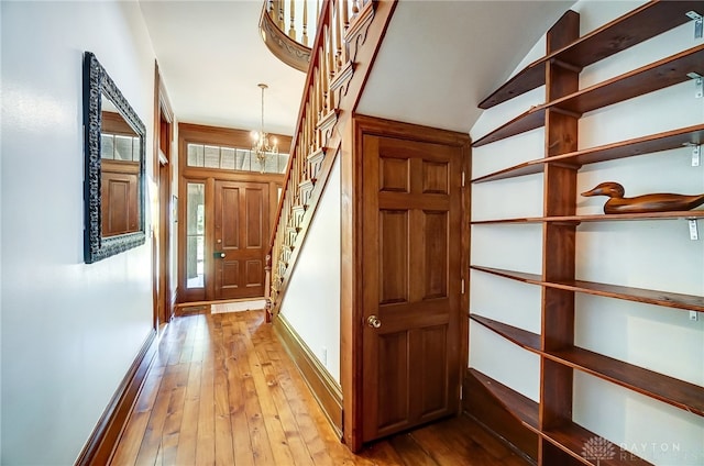 hall featuring lofted ceiling, a chandelier, and light hardwood / wood-style floors