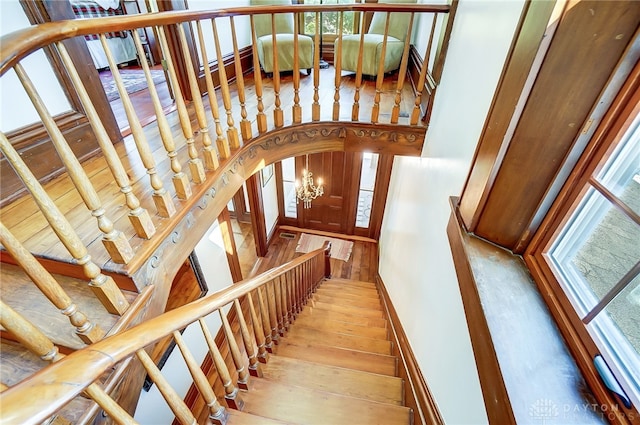 stairway featuring an inviting chandelier and hardwood / wood-style flooring