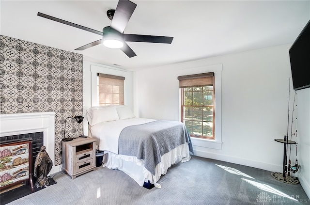 carpeted bedroom with ceiling fan and a fireplace