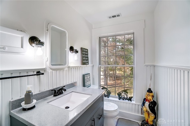 bathroom with a wealth of natural light, vanity, and toilet