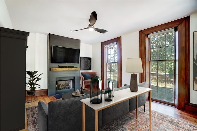 office space featuring a large fireplace, wood-type flooring, and ceiling fan