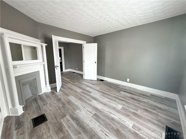 unfurnished living room with a textured ceiling and light hardwood / wood-style flooring