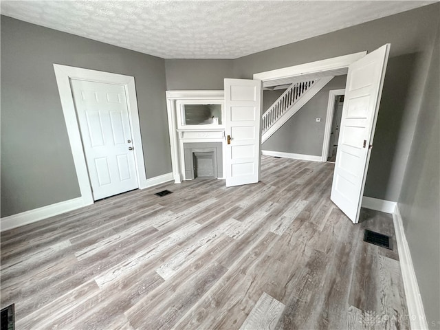 unfurnished living room with a textured ceiling and light hardwood / wood-style floors